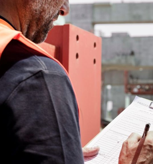 Mann in Arbeitskleidung und mit einem Schreibblock in der Hand